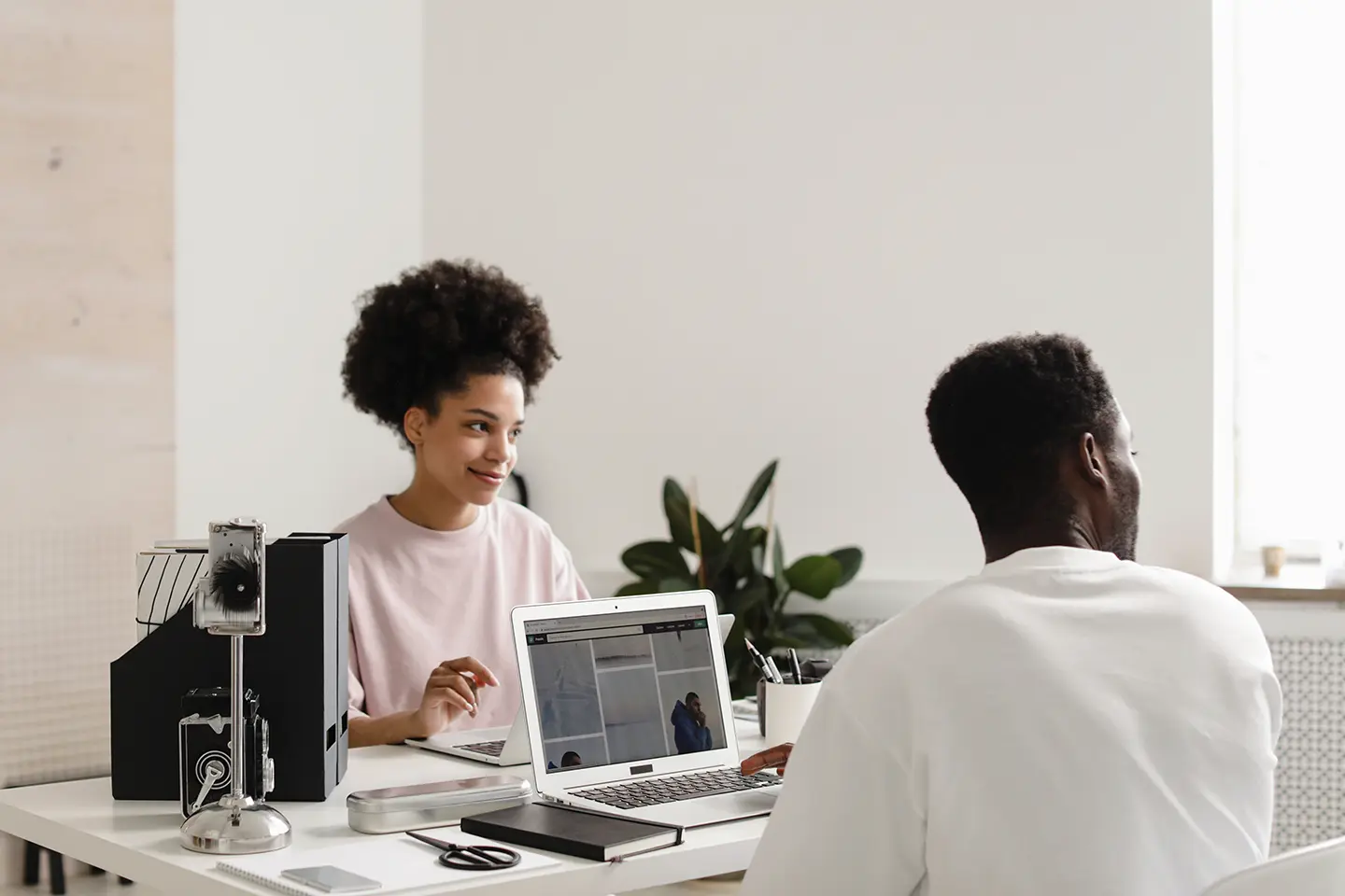Two professionals collaborating at a desk with laptops